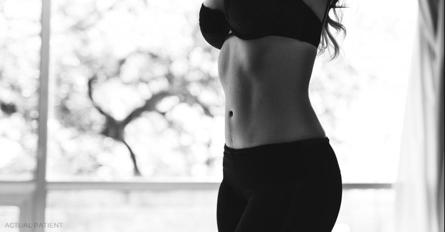 Woman in a black bra top and black pants standing in front of a window
