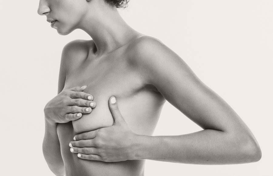 Woman examining her breast, considering breast augmentation revision